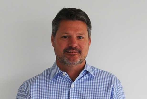 Andy Shape, smiling wearing blue gingham woven shirt