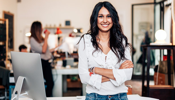 Woman smiling standing next to computer in small business