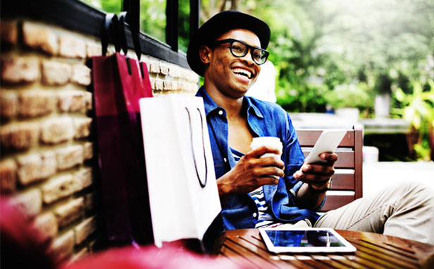 Man at outdoor cafe smiling and drinking coffee