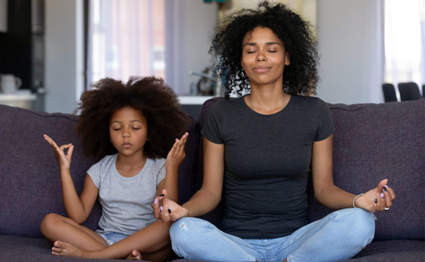 Woman and child meditating on couch