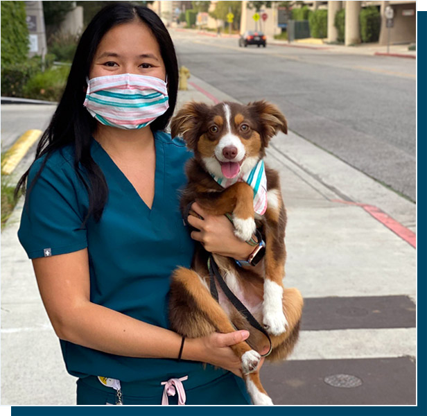 Tandy Tiramai standing on city sidewalk holding dog