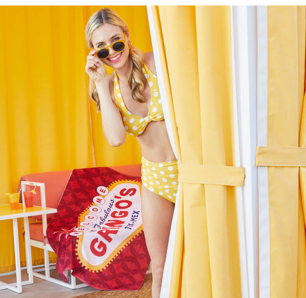 Woman in yellow polka-dot bikini with towel in background