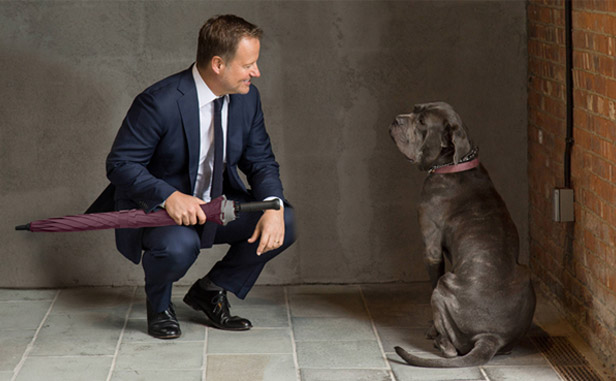 Rick Reichmuth holding umbrella looking at dog