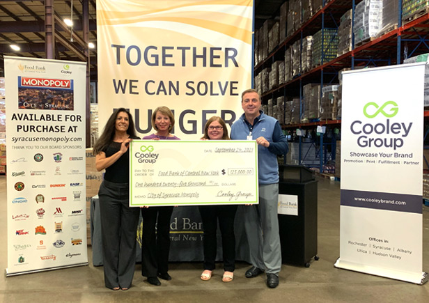 three women and one man holding up large check