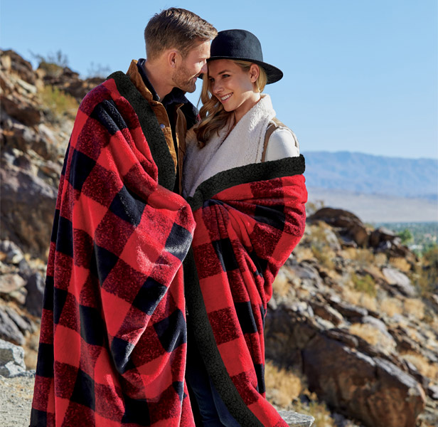 man and woman wrapped in red and black checkered plush blanket