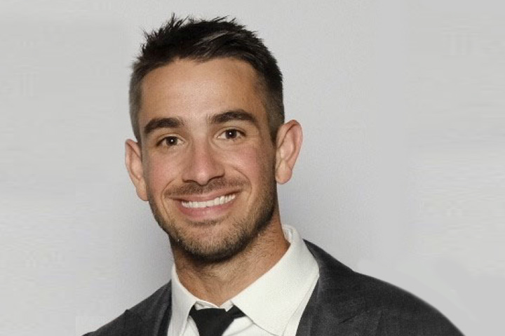 dark-haired young man wearing suit and tie, smiling