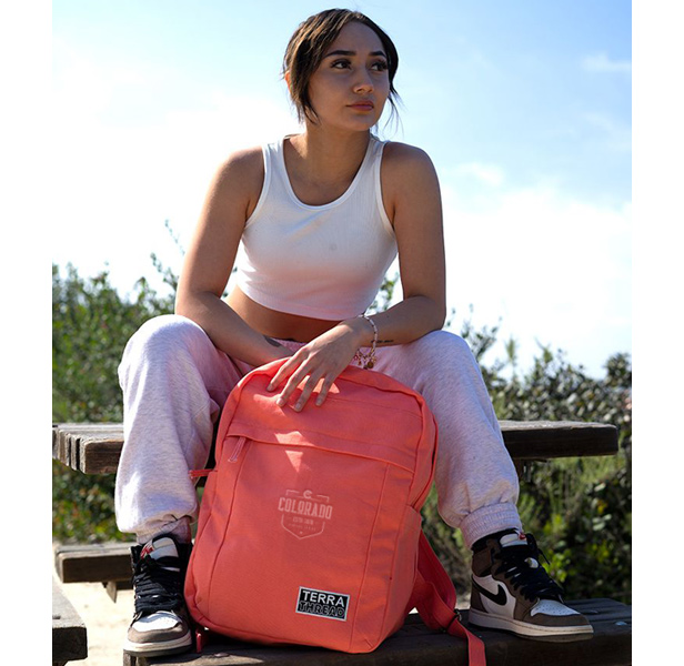 woman sitting on bench holding orange backpack