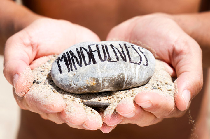 hands holding a rock painted with word mindfulness