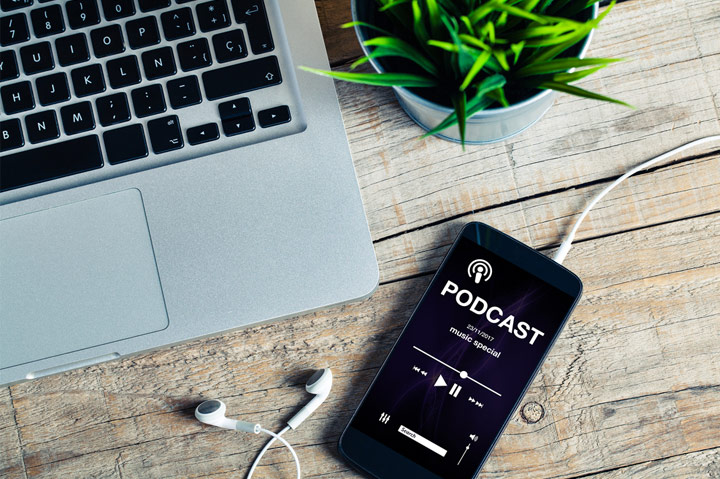 podcast app on phone next to laptop