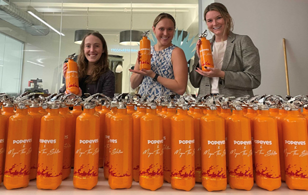 Harper + Scott employees showing off Popeye's water bottles