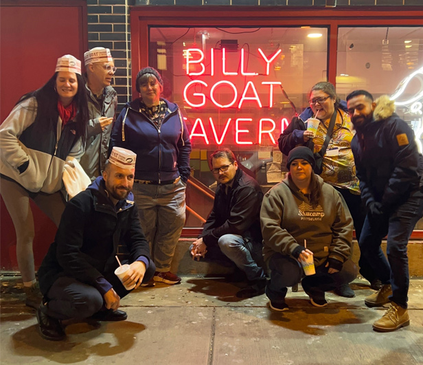 Printable Promotions employees outside Billy Goat Tavern, red neon sign in background