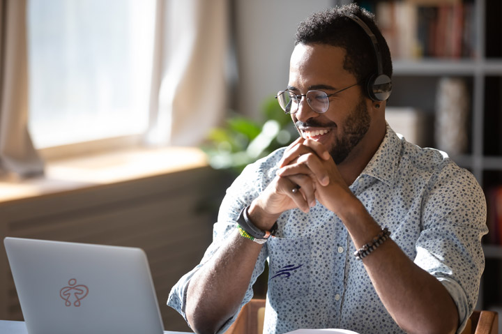 happy millennial man smiling while looking at computer