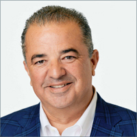 John McMaude smiling, wearing blue blazer and white collared shirt