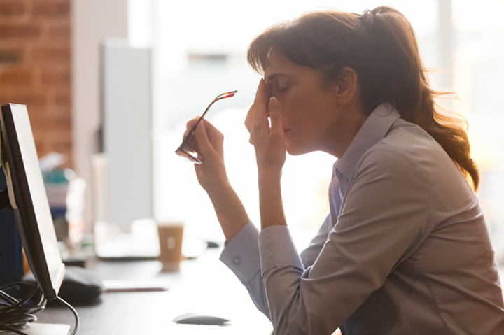 exhausted female worker rubbing eyes while sitting at desk