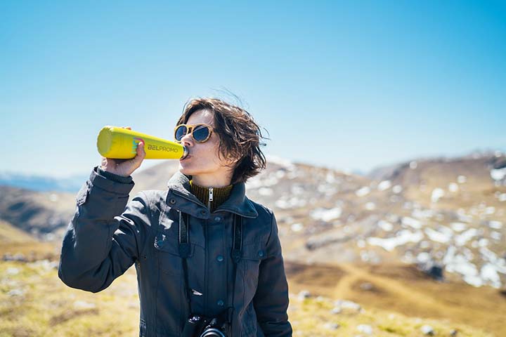 Young woman drinking out of a yellow water bottle