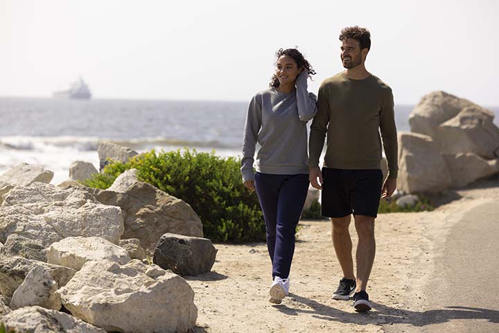 Young people walking on beach in Next Level Apparel clothing