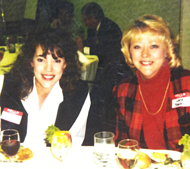 two women sitting together at table, smiling