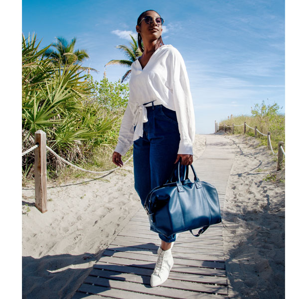 woman on beach carrying blue leather bag