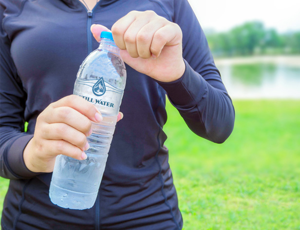 woman holding water bottle, green grass in background