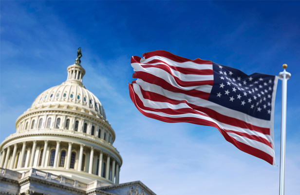 Capitol building, US flag waving in foreground