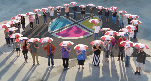 Quinn group photo of employees holding umbrellas