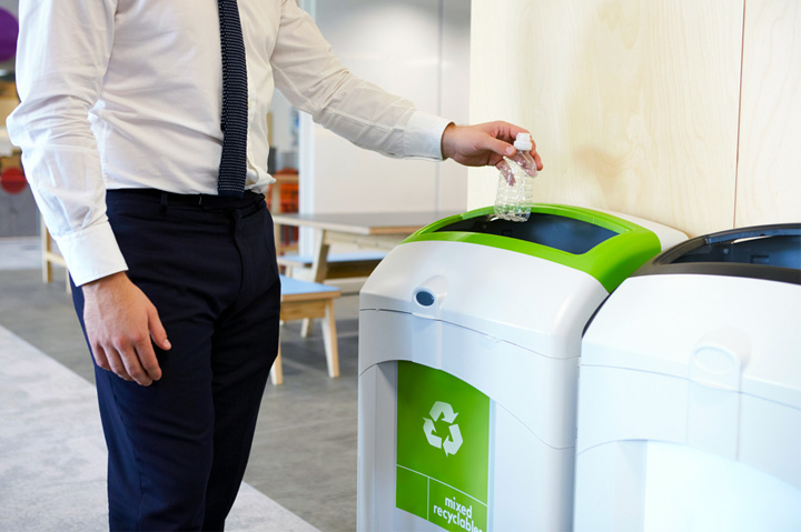 man throwing plastic bottle into recycling container