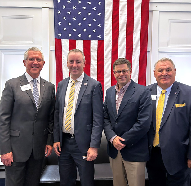 four men standing in front of U.S. flag