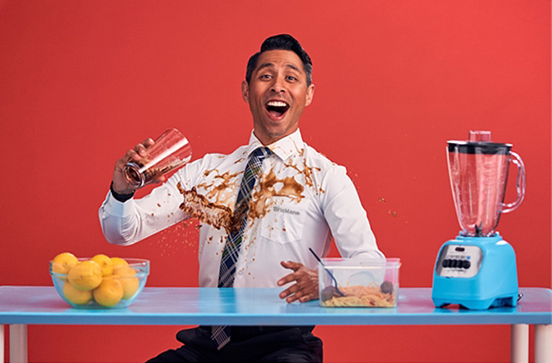 man spilling a drink on his white shirt, laughing