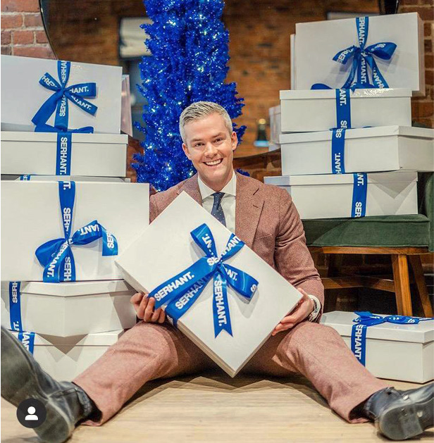 man sitting in front of tower of boxes wit ribbon