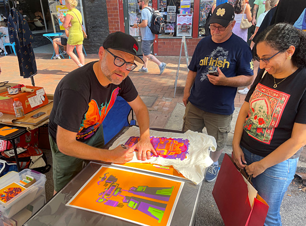 illustrator Tom Whalen signing t-shirt